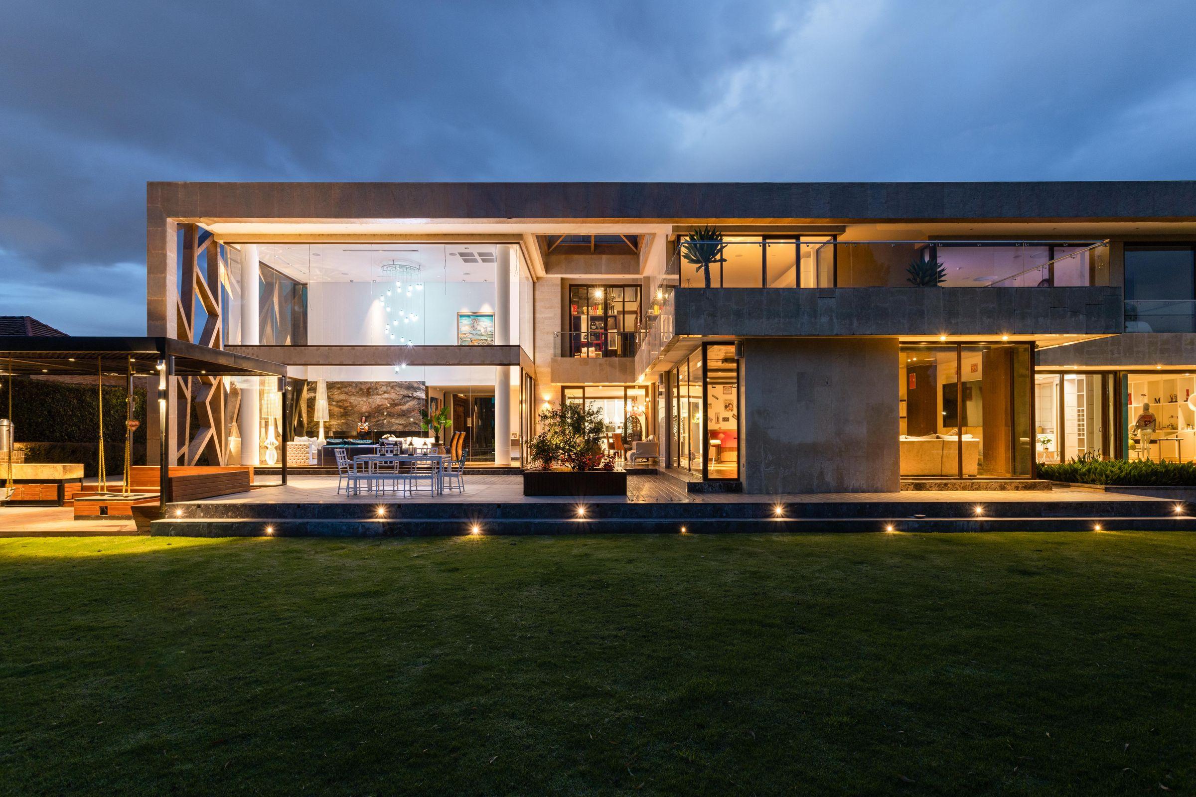 An illuminated contemporary residence with detailed stone, glass and landscaped finishes